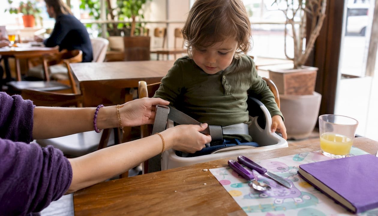 Parents adjusting child booster seat at outdoor café