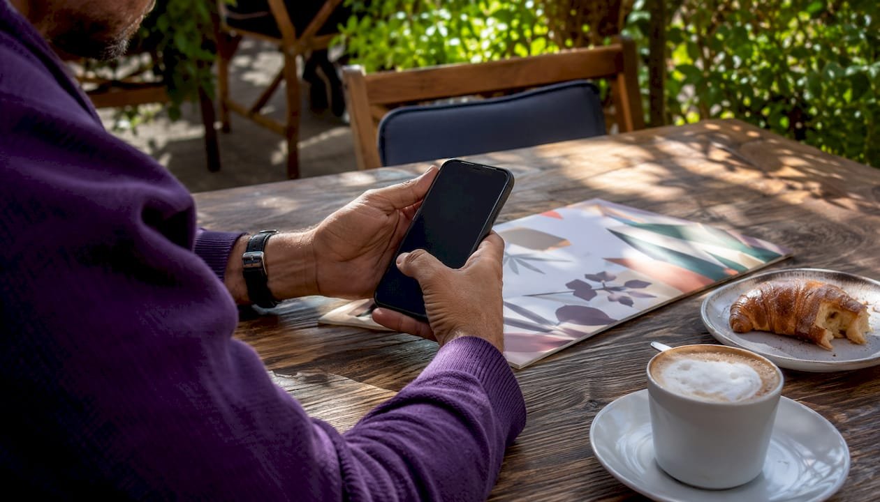 Hands holding smartphone with restaurant menu on table