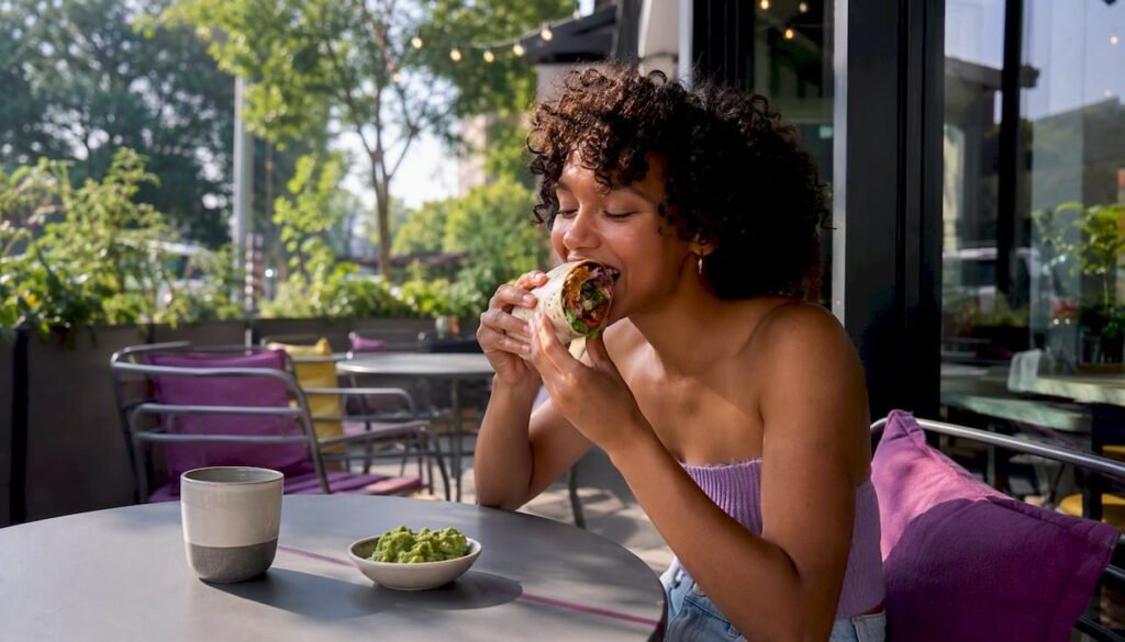 Person eating vegan burrito in restaurant
