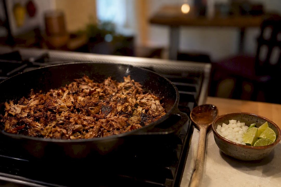 Slow-cooked carnitas crisping in a pan at home
