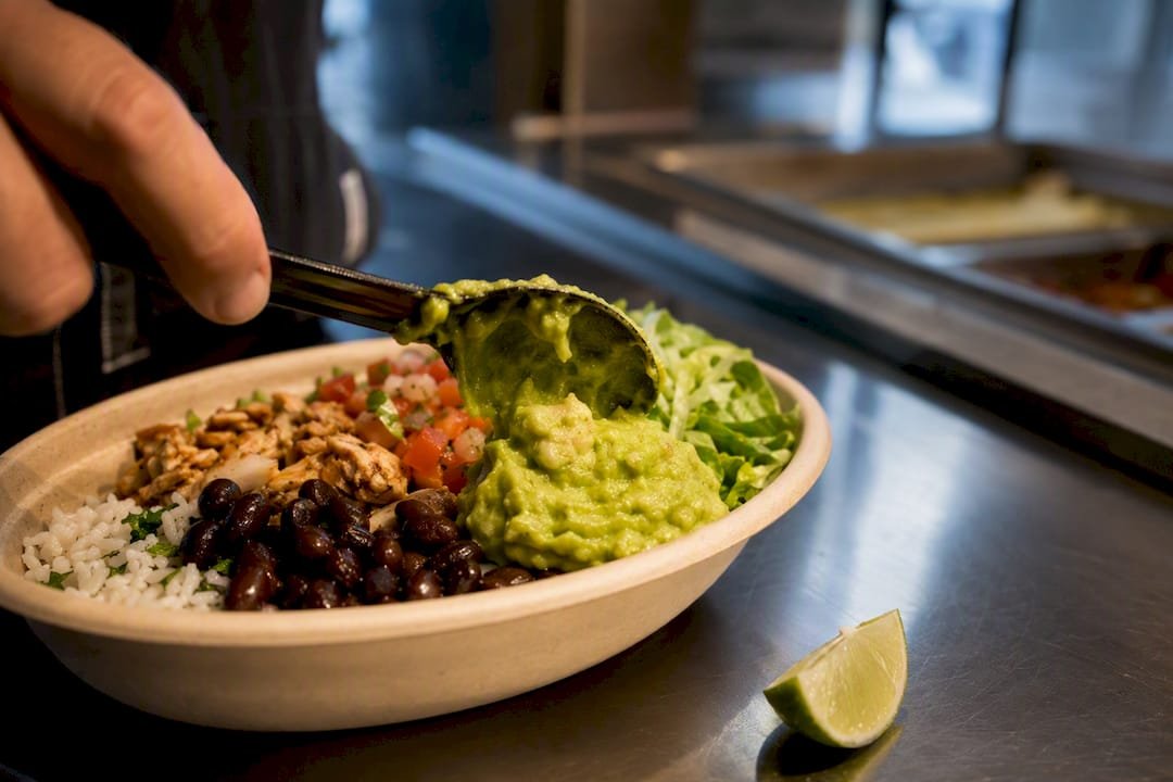 Guacamole added to a burrito bowl