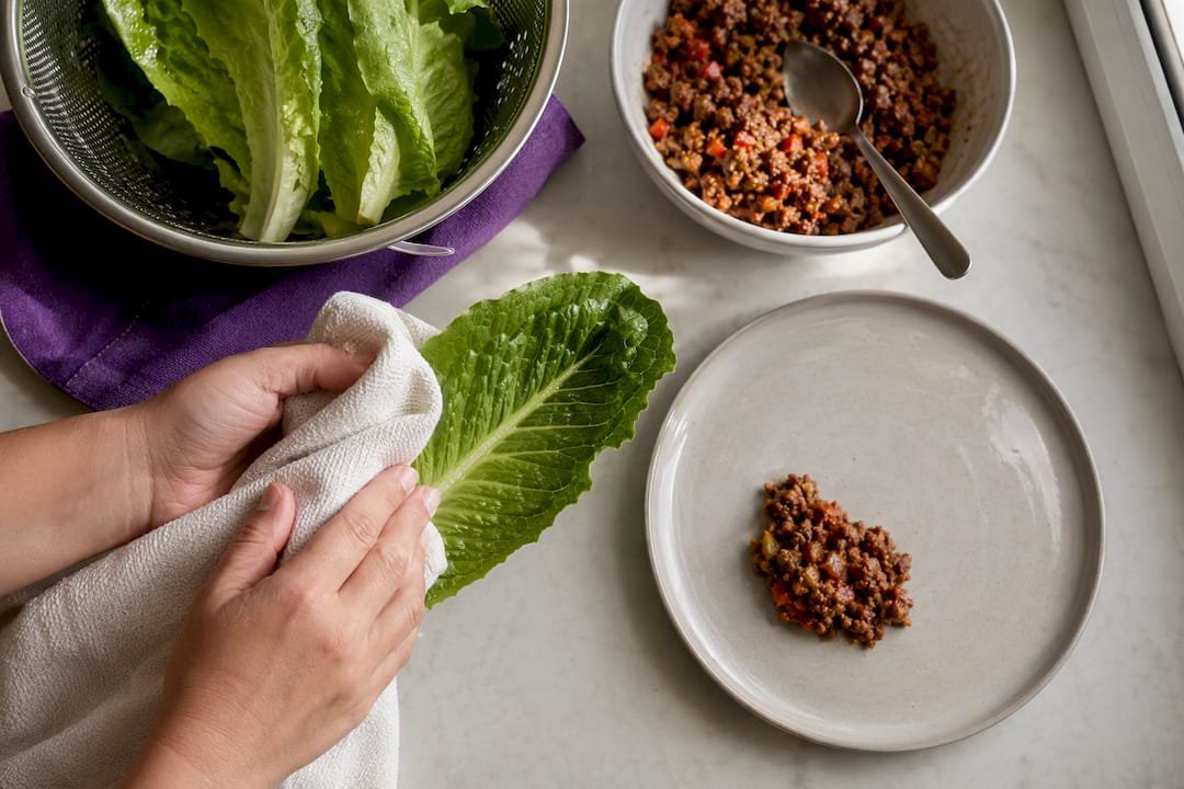 Dry lettuce leaves beside measured taco filling
