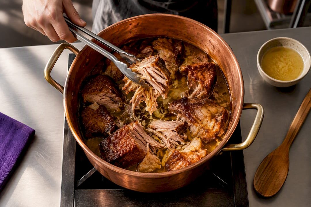 Pork shoulder cooking in copper cazo