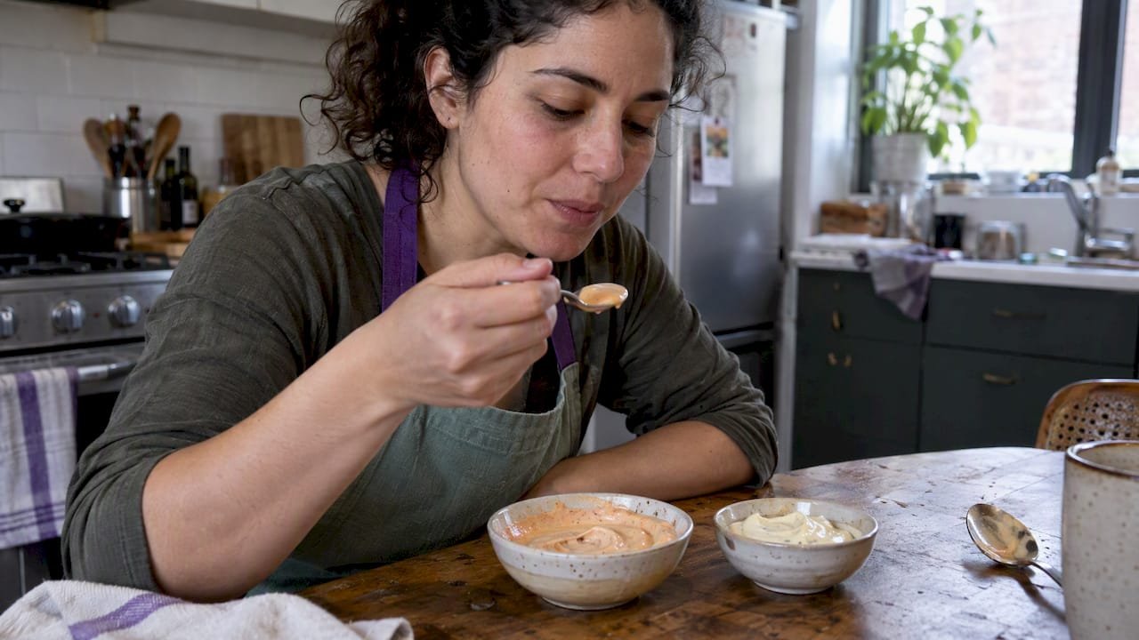 Cook tasting chipotle mayo beside garlic aioli