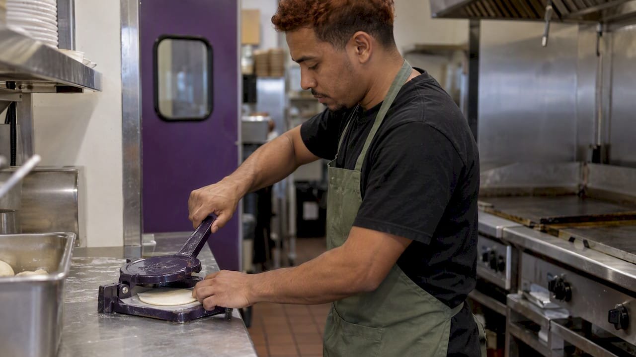 Restaurant worker pressing a fresh tortilla