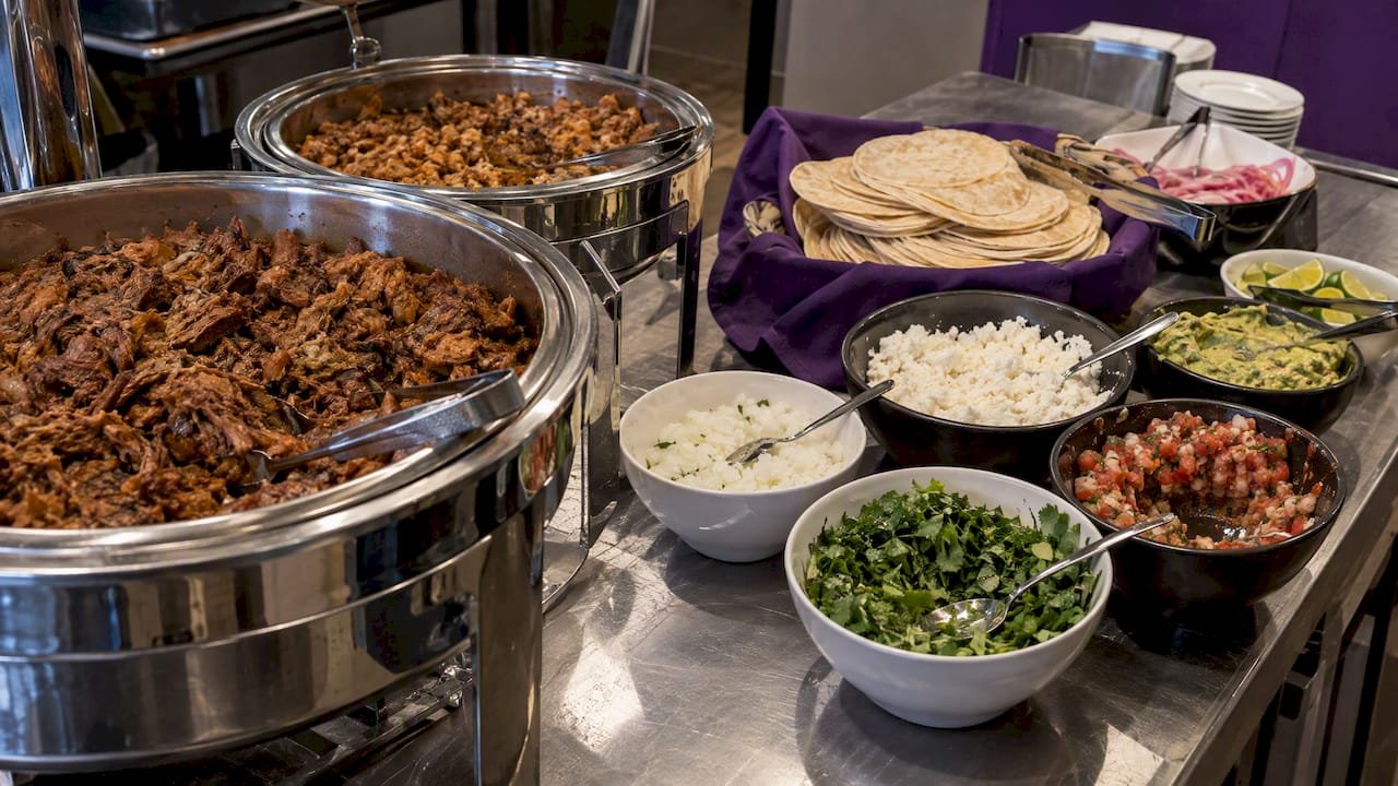 Tortillas, braised meat, and toppings at a buffet